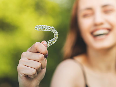 The image features a person holding up a clear plastic tray with a toothbrush inside, showcasing its bristles.