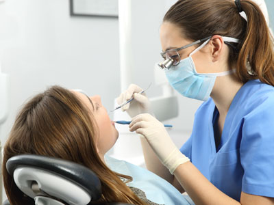 A dental hygienist attending to a patient s teeth while seated in a dental chair.