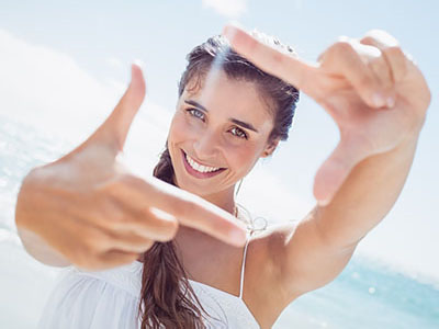 A woman taking a selfie with her right hand while smiling at the camera.